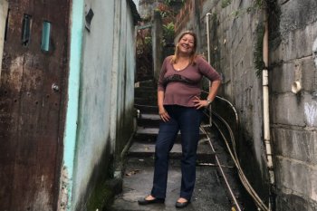 Rita stands near her home.